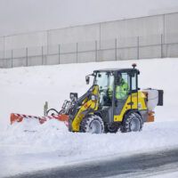 Pala cargadora compacta Wacker Neuson WL250 trabajando en retirada de nieve en exteriores.